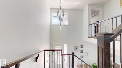 Two-story foyer featuring an ornamental chandelier, upper transom window, and dark wood-finish staircase with wrought iron balusters - 1103 30 Street Nw, Edmonton, AB 
