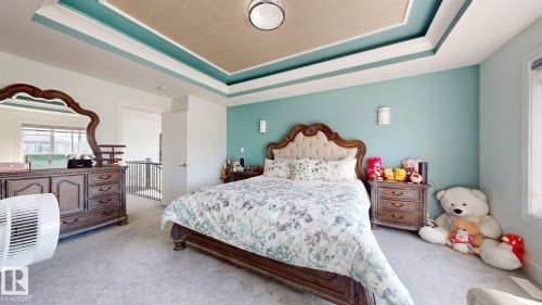 Recessed tray ceiling with accent lighting, light-colored carpeting, white trim work, and a window with natural light - 1103 30 Street Nw, Edmonton, AB 