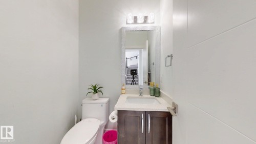 Powder room featuring a modern vanity with dark wood-finish cabinetry, light-toned countertop, and a rectangular undermount sink - 1103 30 Street Nw, Edmonton, AB 