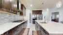 Kitchen with dark wood-finish cabinetry, light-toned countertops, and a full tile backsplash - 1103 30 Street Nw, Edmonton, AB 