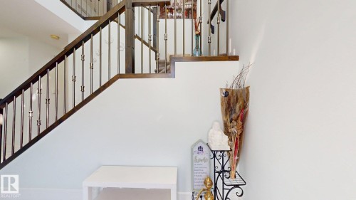 Staircase featuring dark wood-finish handrails, metal balusters, and white risers - 1103 30 Street Nw, Edmonton, AB 