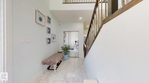 White tiled flooring, high ceilings, wood and metal staircase railing, recessed lighting, and a sliding glass door - 1103 30 Street Nw, Edmonton, AB 