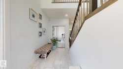 White tiled flooring, high ceilings, wood and metal staircase railing, recessed lighting, and a sliding glass door - 