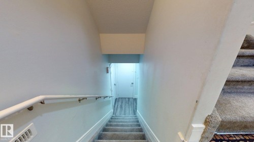Carpeted staircase with white handrail and wood-finish flooring at landing - 1103 30 Street Nw, Edmonton, AB 