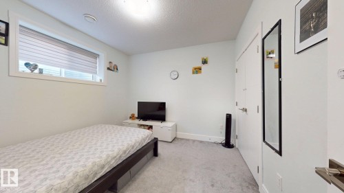 Light-toned walls with a window featuring horizontal blinds, complemented by light grey carpeting, and white doors with brushed metal hardware - 1103 30 Street Nw, Edmonton, AB 