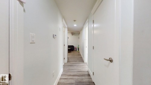 Hallway featuring wood-finish flooring, recessed lighting, and white panel doors with brushed nickel hardware - 1103 30 Street Nw, Edmonton, AB 