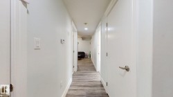 Hallway featuring wood-finish flooring, recessed lighting, and white panel doors with brushed nickel hardware - 