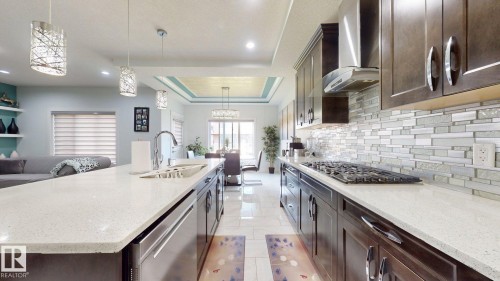 Kitchen featuring dark wood-finish cabinetry, light-toned countertops, and a full-height mosaic tile backsplash - 1103 30 Street Nw, Edmonton, AB 