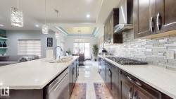 Kitchen featuring dark wood-finish cabinetry, light-toned countertops, and a full-height mosaic tile backsplash - 