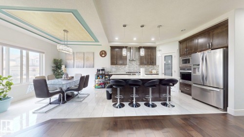 Gleaming tile flooring, wood-finish flooring, a tray ceiling with recessed lighting, an island with countertop seating, and stainless steel appliances - 1103 30 Street Nw, Edmonton, AB 