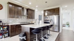 Kitchen featuring rich wood cabinetry, stainless steel appliances, a center island with countertop seating, and a mosaic tile backsplash - 