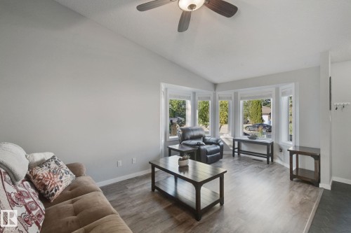 Vaulted ceiling, wood-finish flooring, bay window, ceiling fan with integrated lighting, and a distinct entry area - 38 Menalta Place, Cardiff, AB 
