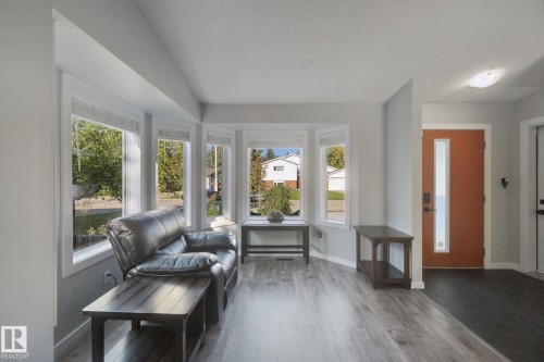 Bay window with multiple panes, wood-finish flooring, recessed lighting, and a front entry door with vertical glass insert - 38 Menalta Place, Cardiff, AB 