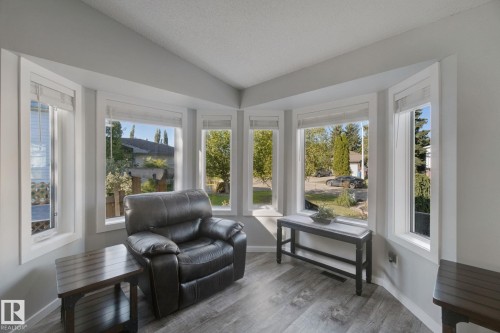 Bay window with multiple large panes, light gray wall paint, and wood-finish flooring - 38 Menalta Place, Cardiff, AB 