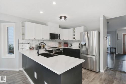 Modern kitchen with white and black cabinetry, white countertops, subway tile backsplash, and stainless steel appliances - 38 Menalta Place, Cardiff, AB 