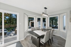 Dining area featuring wood-finish flooring, a contemporary chandelier, and a bay window with multiple panes - 