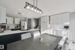 Kitchen featuring white upper cabinetry, dark lower cabinetry, stainless steel appliances, and a subway tile backsplash - 