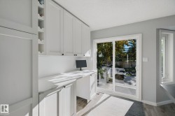 Built-in desk area, white cabinetry, integrated wine storage, sliding glass patio door, and wood-finish flooring - 