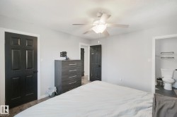 Light gray wall paint, wood-finish flooring, ceiling fan, six-panel interior doors, and a white toilet - 