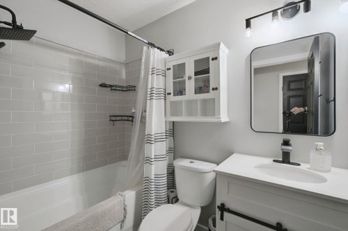 White vanity with integrated sink, black single-handle faucet, and rectangular mirror - 38 Menalta Place, Cardiff, AB 