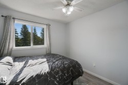 White walls, wood-finish flooring, and a ceiling fan with integrated lighting - 