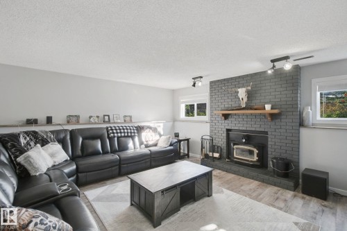 Painted brick fireplace with wood mantel and wood-burning insert - 38 Menalta Place, Cardiff, AB 