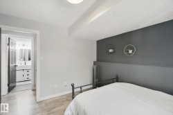 Wood-finish flooring, accent wall, and a full bathroom with a vanity, rectangular sink, and attached mirror - 