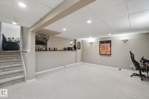 Finished lower level with recessed lighting, wall sconces, carpet flooring, a built-in bar, and a carpeted staircase - 38 Menalta Place, Cardiff, AB 