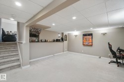 Finished lower level with recessed lighting, wall sconces, carpet flooring, a built-in bar, and a carpeted staircase - 