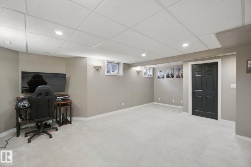 Recessed lighting with sconce accents, neutral wall color, light-toned carpet flooring, drop ceiling, and a dark paneled door - 38 Menalta Place, Cardiff, AB 