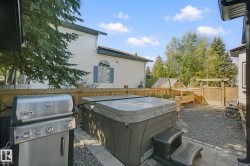 Enclosed backyard with a hot tub, gravel surfacing, and wood fencing - 