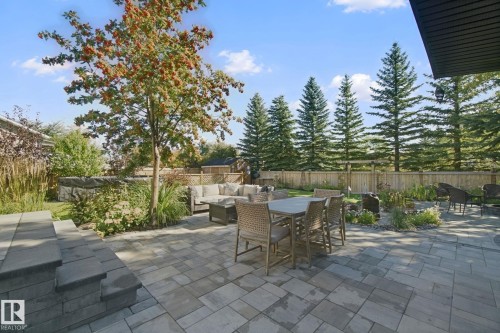 Paver patio, terraced landscaping, mature trees, wooden privacy fence, and integrated planters - 38 Menalta Place, Cardiff, AB 