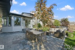 Paver patio with an elevated section, featuring mature trees and established landscaping - 