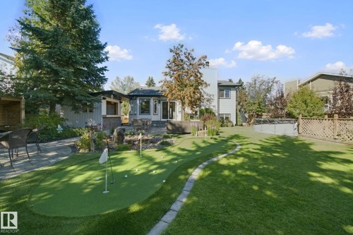Expansive backyard featuring a putting green, a stone patio, and mature trees - 38 Menalta Place, Cardiff, AB 