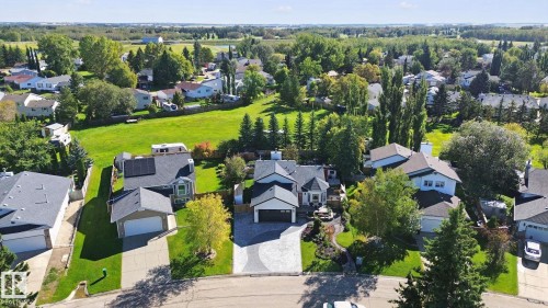 Residential property featuring an asphalt shingle roof, attached garage, and mature landscaping - 38 Menalta Place, Cardiff, AB 