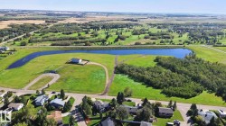 Expansive green space featuring a large pond, adjacent wooded areas, and surrounding cultivated fields - 