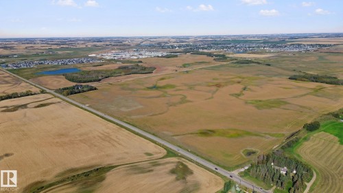 Expansive land parcel featuring open fields and distant suburban development - 38 Menalta Place, Cardiff, AB 