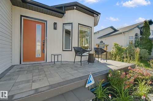 Inviting front entry with a vibrant orange door, rectangular transom window, and a modern exterior light fixture - 38 Menalta Place, Cardiff, AB 