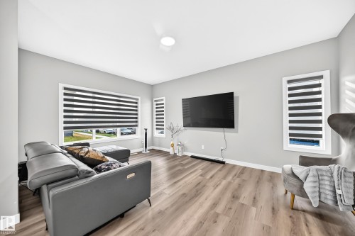 Spacious living area featuring light wood-finish flooring, light gray wall paint, and white trim - 2415 194 Street Nw, Edmonton, AB 
