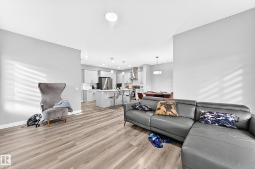 Open-concept interior featuring wood-finish flooring, recessed lighting, and a kitchen with stainless steel appliances, a center island, and pendant lighting - 2415 194 Street Nw, Edmonton, AB 