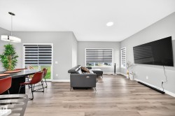 Spacious living area featuring wood-finish flooring, ample natural light, recessed ceiling lighting, and a modern dining pendant light - 
