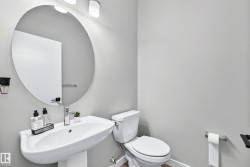 Pedestal sink with chrome faucet, circular wall-mounted mirror, and white toilet - 
