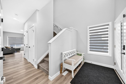 Entryway featuring wood-finish flooring, white panel doors, and a staircase with carpeted treads - 2415 194 Street Nw, Edmonton, AB 