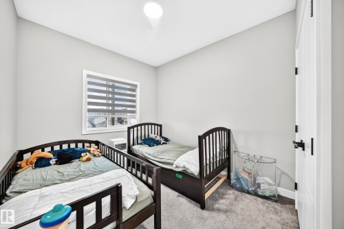 Light gray painted walls, window with horizontal blinds, overhead flush mount lighting, gray carpeted flooring, and a white paneled door with black hardware - 2415 194 Street Nw, Edmonton, AB 