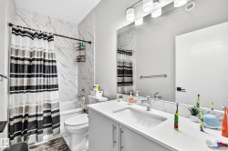 Modern bathroom featuring a single vanity with a white countertop and undermount sink, a large wall mirror, and a built-in bathtub with subway tile surround - 