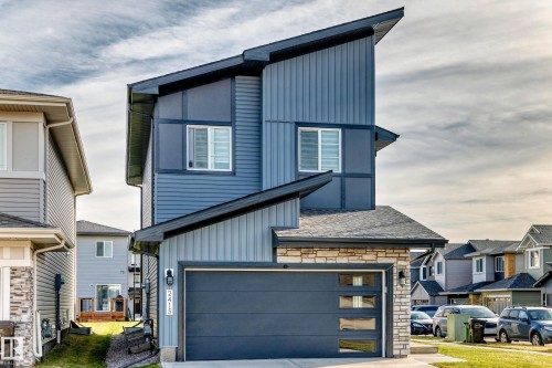Contemporary exterior with angled roofline, vertical siding, stone accents, and an integrated garage with frosted glass panels - 2415 194 Street Nw, Edmonton, AB 