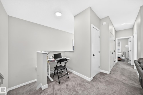 Carpeted hallway with white interior doors, black hardware, and overhead lighting - 2415 194 Street Nw, Edmonton, AB 