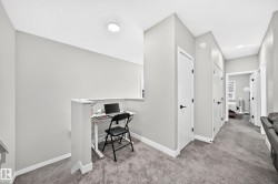 Carpeted hallway with white interior doors, black hardware, and overhead lighting - 