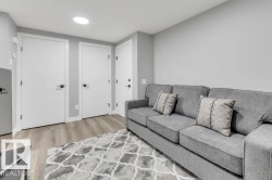 Recessed ceiling lighting, light gray wall finishes, wood-finish flooring, white doors with black hardware - 