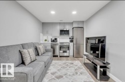 Compact kitchen with stainless steel appliances, light gray cabinetry, and white countertops - 